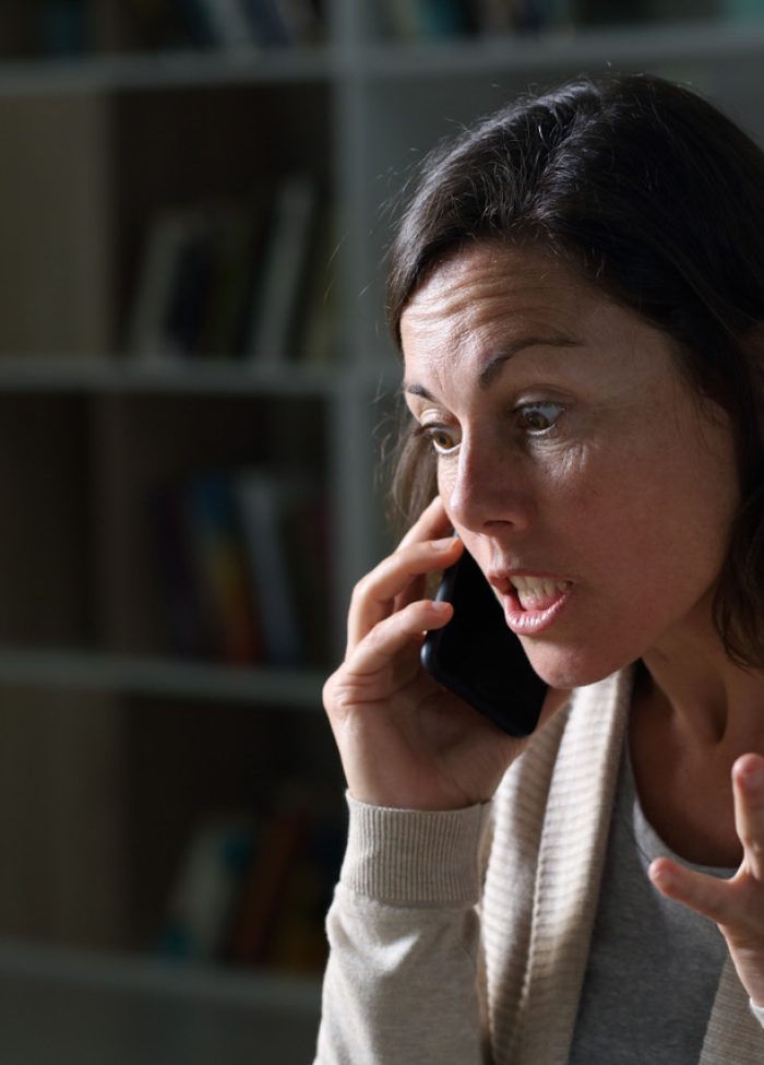 Angry middle age woman calling on phone at night at home